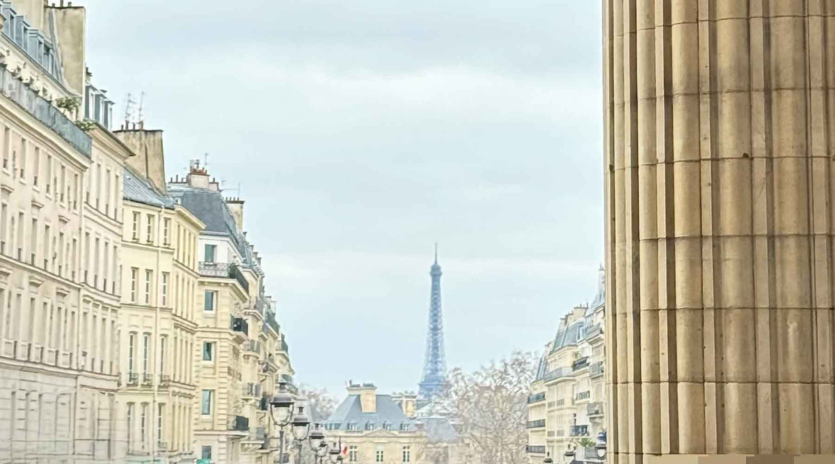 Eiffel Tower framed between Parisian buildings under a calm grey sky, representing structure and intentional living
