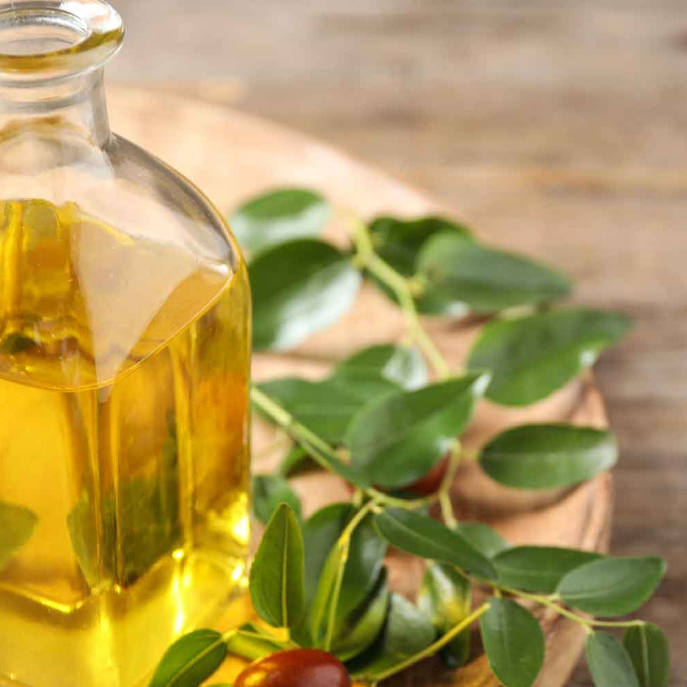 Elegant glass bottle of jojoba oil surrounded by scattered jojoba seeds, showcasing the natural and pure essence of the oil in a sophisticated setting